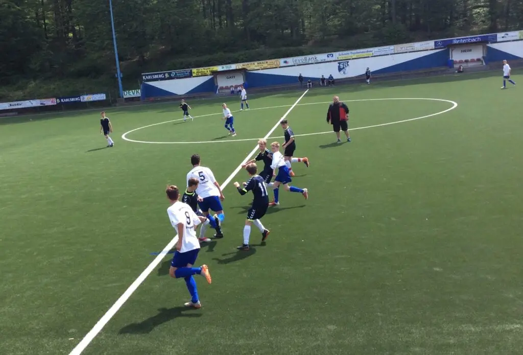 Schülermannschaften spielen Fußball auf einem Kunstrasenplatz im Stadion