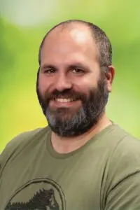 Porträt Andreas Backes, mit Bart im olivgrünen T-Shirt vor grünem Hintergrund