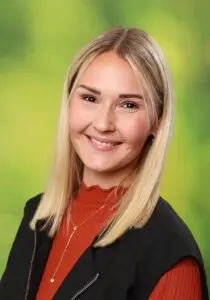 Porträt Katharina Britz, mit langen blonden Haaren vor grünem Hintergrund