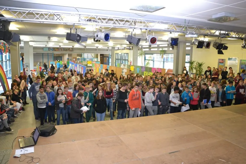 Blick von der Bühne über die gefüllte Aula mit vielen Schülerinnen und Schülern