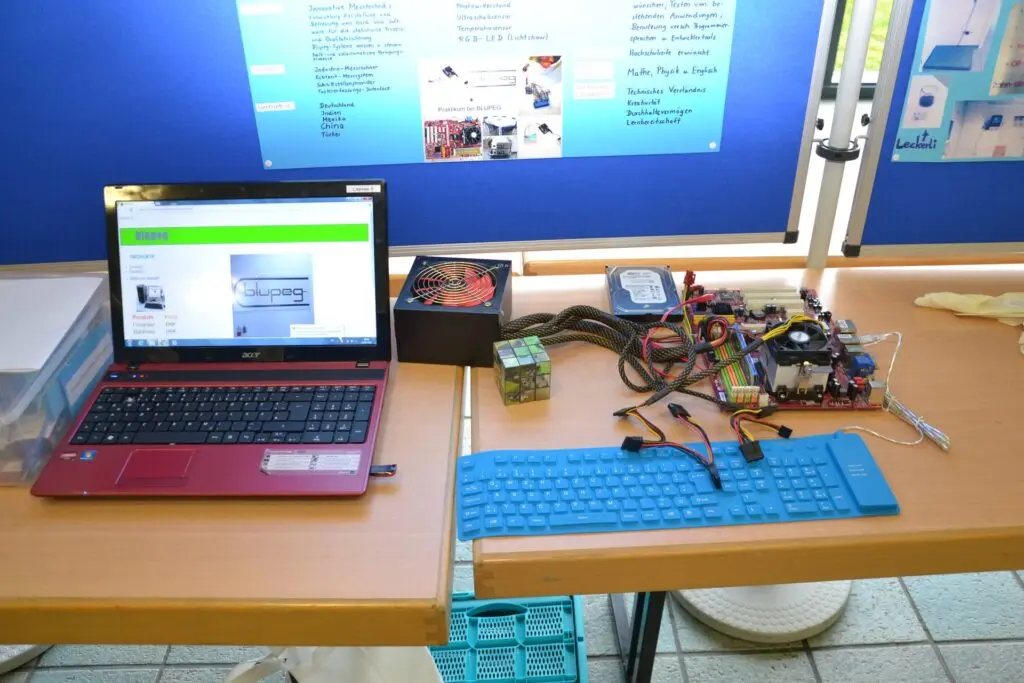 Laptop, Tastatur und Elektronikbauteile auf einem Tisch an einem Infostand