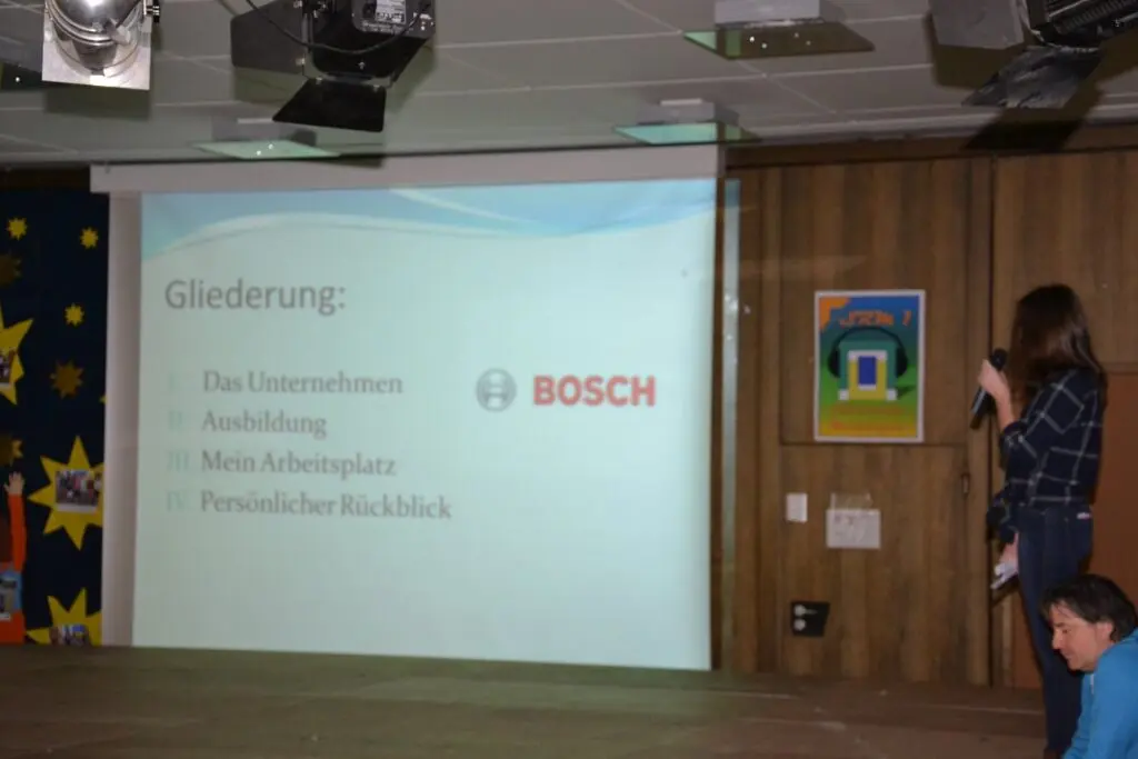 Schülerin präsentiert auf der Bühne eine Folie mit Bosch-Logo zur Gliederung