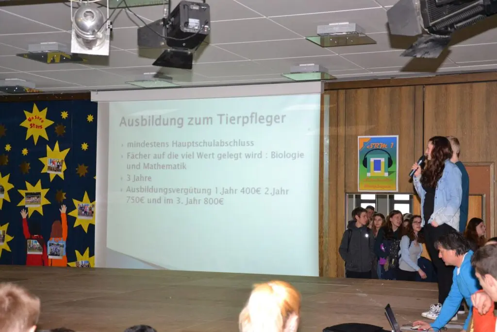 Schülerinnen präsentieren auf der Bühne eine Folie zur Ausbildung zum Tierpfleger