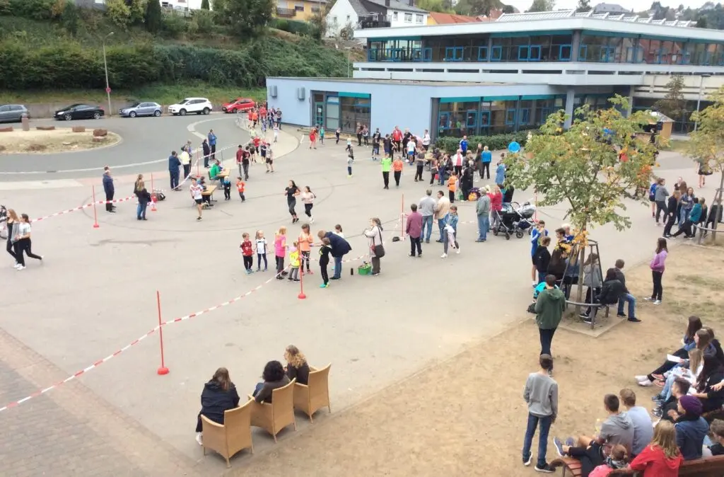 Schülerinnen und Schüler auf dem Schulhof bei einer Laufveranstaltung, Blick von oben