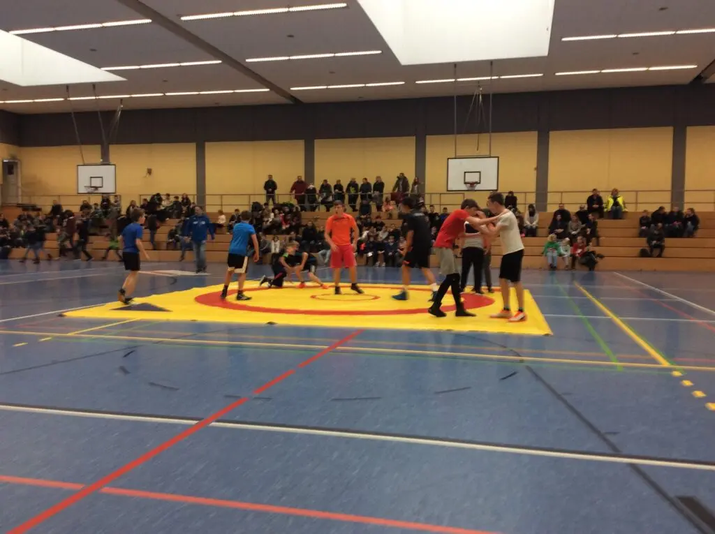 Ringerturnier in einer großen Sporthalle, mehrere Ringermatten, im Hintergrund Zuschauer