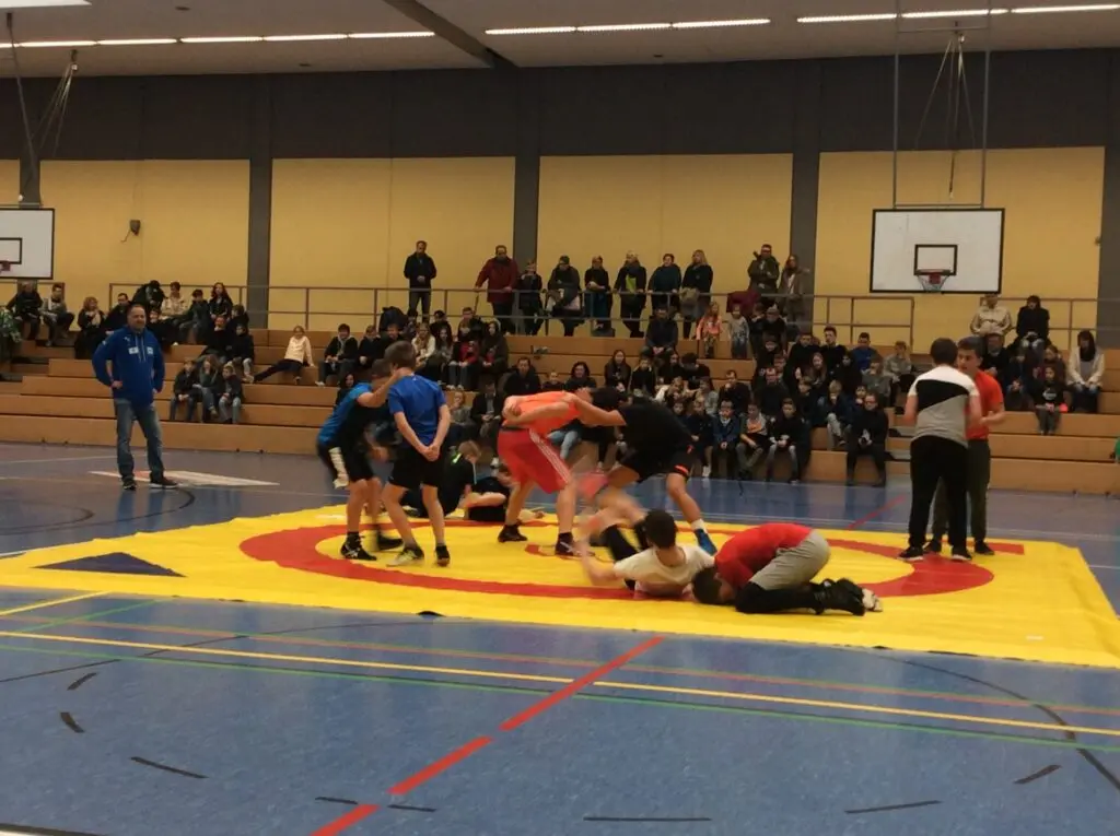 Ringkämpfe am Boden auf einer Matte in einer großen Sporthalle mit vielen Zuschauern