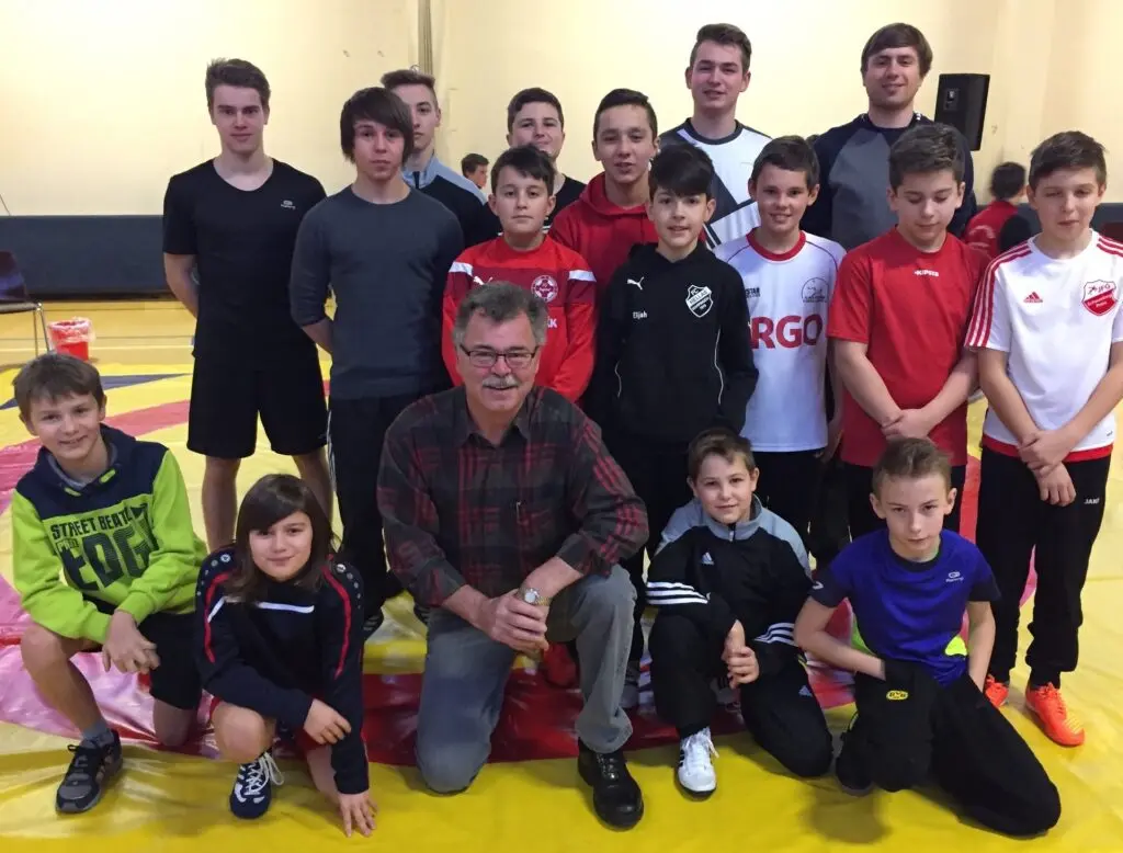 Gruppenfoto junger Ringer mit Trainern auf einer Ringermatte in der Sporthalle