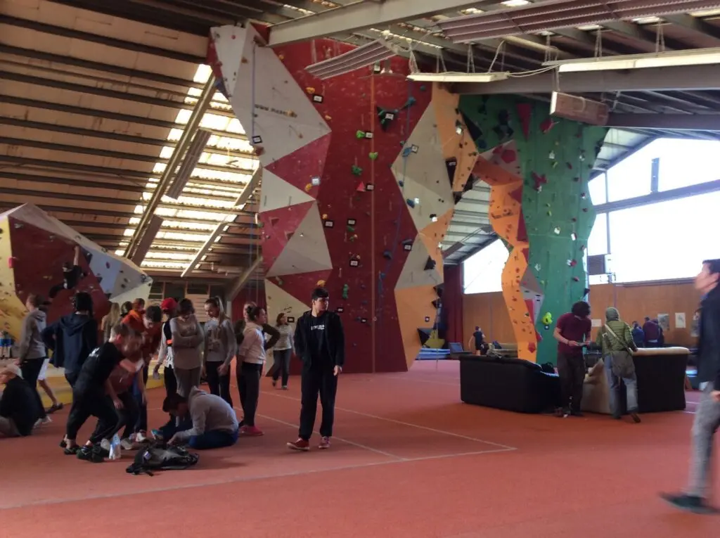 Zuschauer und Teilnehmende in einer großen Kletterhalle mit hohen Wänden