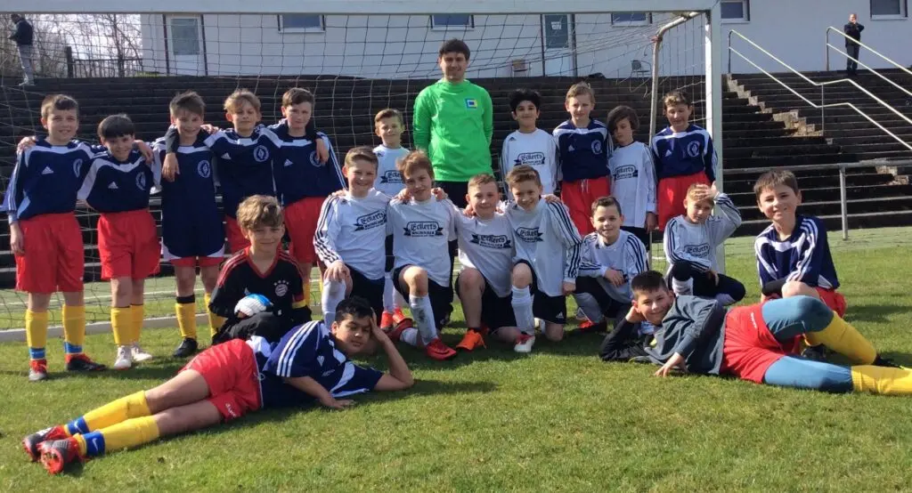Fußballteam in blauen und weißen Trikots posiert auf einer Rasenfläche