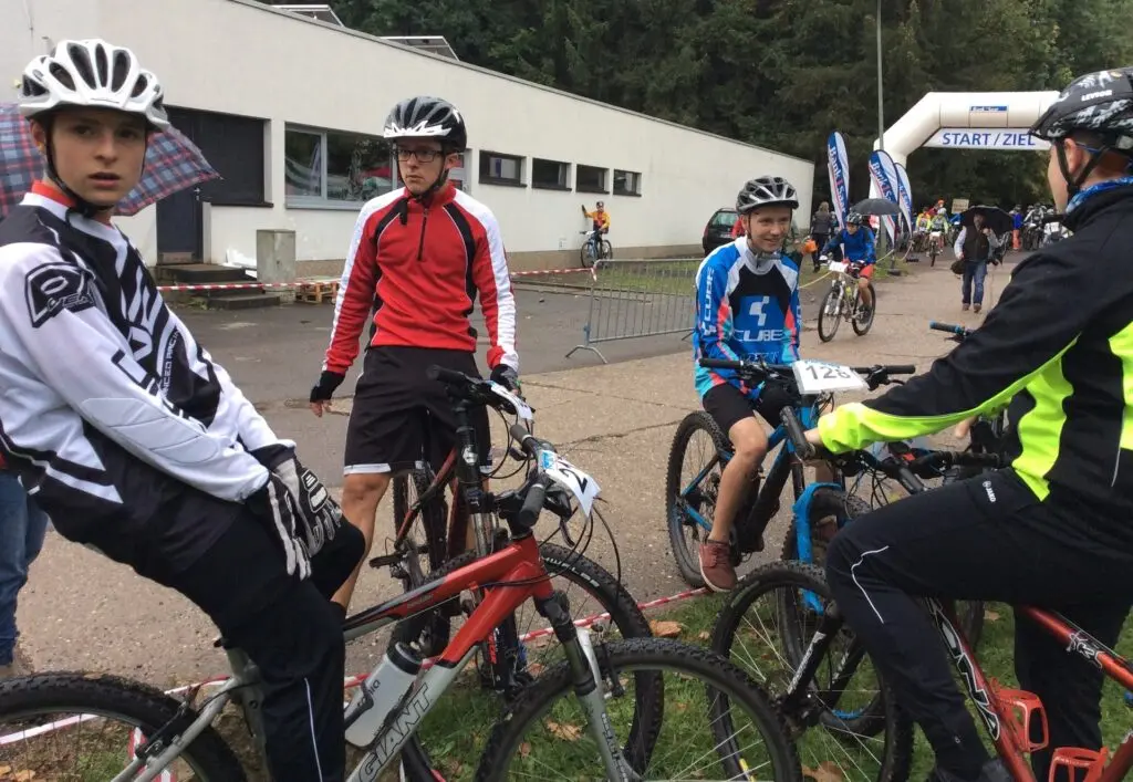 Jugendliche mit Helmen auf Mountainbikes beim Start eines Rennens
