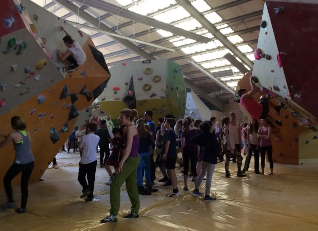 Schülergruppen in einer großen Kletterhalle mit bunten Wänden