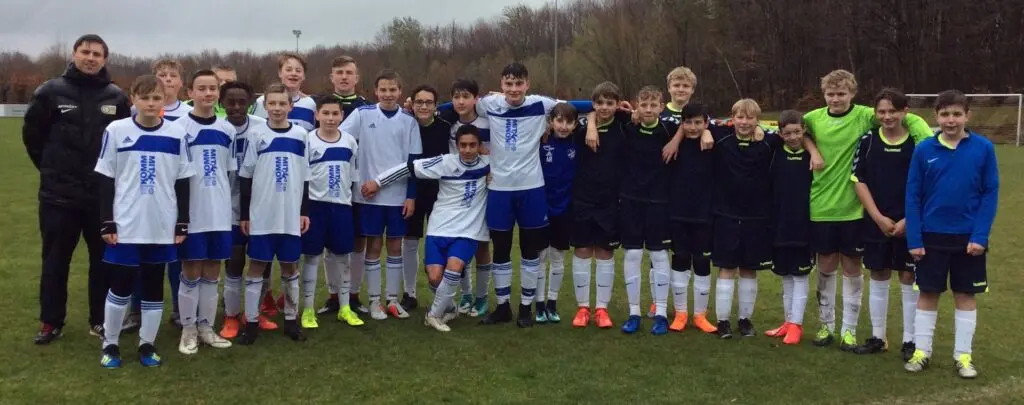 Zwei Fußballteams stehen nebeneinander auf dem Rasen eines Stadions