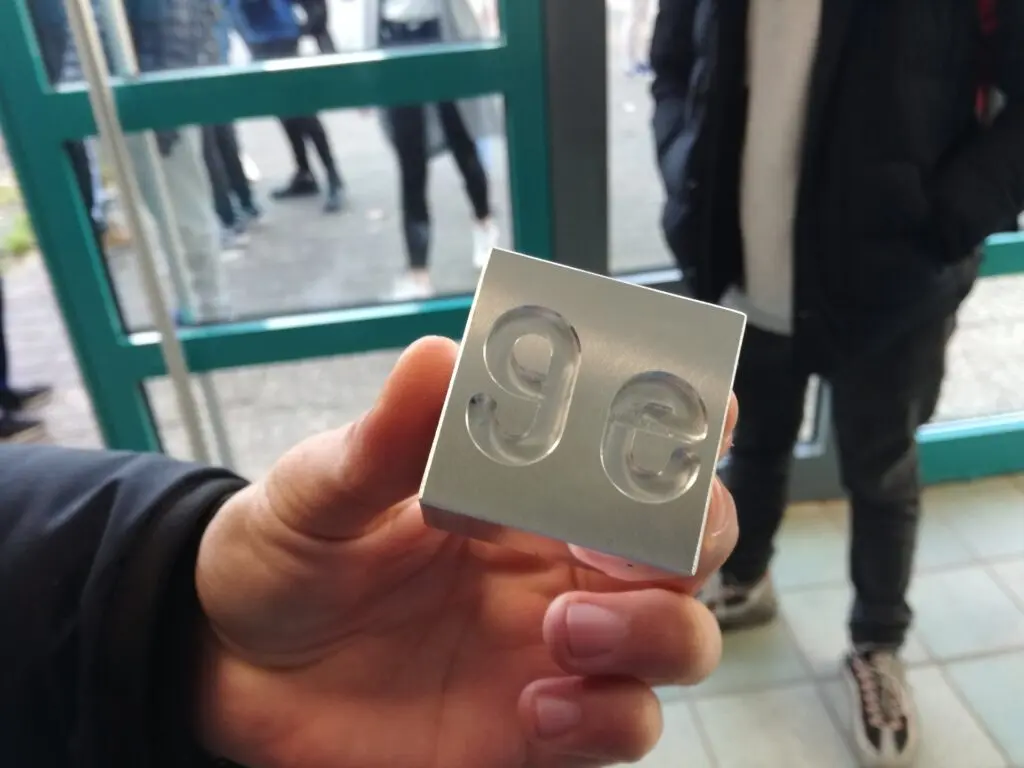 Hand hält ein selbst tiefgezogenes Kunststoffteil mit zwei Mulden, im Hintergrund eine Glastür