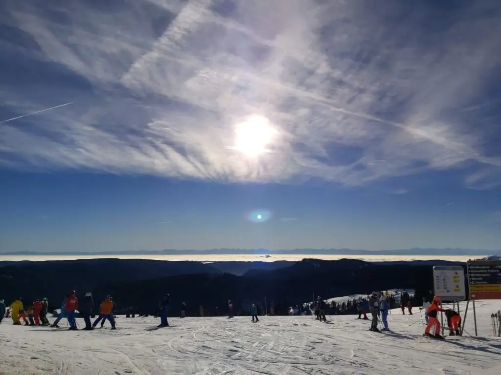 Sonne und Schleierwolken über einem weiten Skigebiet mit vielen Skifahrern