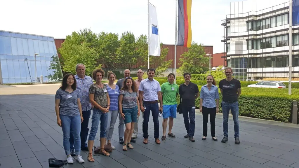 Schülergruppe steht vor einem modernen Firmengebäude mit Fahnen