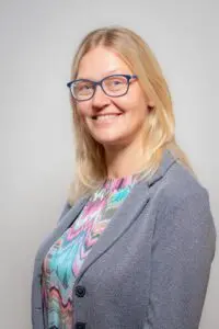 Porträt Susanne Weber, mit Brille und grauem Blazer vor hellem Hintergrund