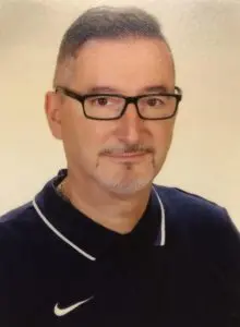 Porträt Anton Maric, mit Brille im dunkelblauen Poloshirt vor hellem Hintergrund