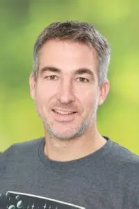 Porträt Jan Wagner, mit kurzen grauen Haaren im grauen T-Shirt vor grünem Hintergrund