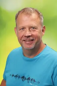 Porträt Georg Wilhelm, im türkisfarbenen T-Shirt vor grünem Hintergrund